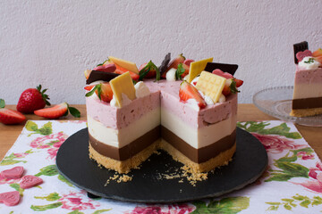 Strawberry, vanilla and chocolate cake decorated with chocolates and strawberries. Neapolitan cake