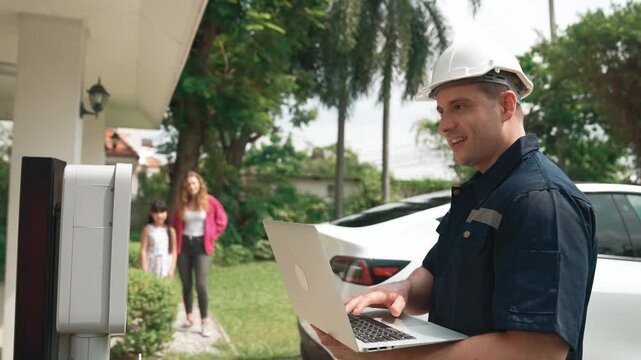 Qualified technician working on home EV charging station installation, making troubleshooting and configuration setup on charging system with laptop for EV at home. Fastidious