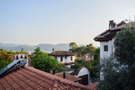 Scenic rooftops of a historic Turkish town Akyaka with charming traditional houses, red-tiled roofs, nestled between the sea and majestic mountains, A picturesque blend of old-world architecture 