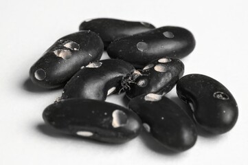 A pile of dried black beans, also known as frijoles negros, is on a clean white backdrop.