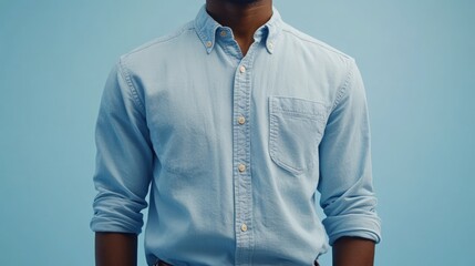 Close-up of a man's light blue, long-sleeved button-down shirt against a pale blue background.