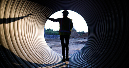 Female Maintenance and Inspection of Waterworks and Irrigation Utilities Equipment Materials and Workers using walkie-talkie to communicate with her team at the sewage  under  construction