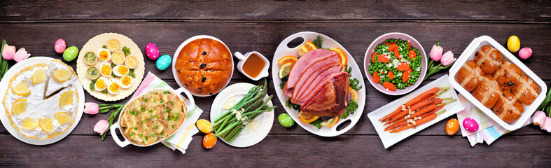 Classic Easter ham dinner. Top view table scene on a dark wood banner background. Ham, scalloped...