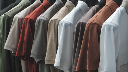 Fototapeta premium A row of shirts hanging on a rack, with the colors ranging from white to brown. The shirts are neatly folded and arranged in a row, creating a sense of order and organization