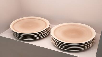 Two stacks of plates with a white background. The plates are white and have a round shape. The plates are stacked neatly on top of each other