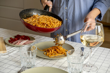 woman hands puts Italian pasta spaghetti bolognese on a plate for dinner or lunch at home