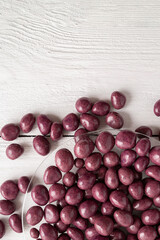 Dried fruits and berries in chocolate glaze. Candies on a white wooden background.