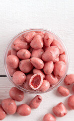 Dried fruits and berries in chocolate glaze. Pink candies on a white wooden background.