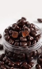 Chocolates with filling in a transparent glass jar. White wooden background. Close-up.
