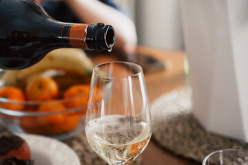Pouring white wine or Prosecco into a glass from a bottle for an aperitif or dinner 