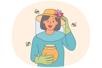 Woman beekeeper holds jar of honey, standing among flying bees, uses net and gloves to protect skin
