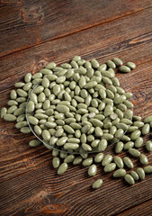 Green chocolates on a brown wooden background. Sweets in a glass plate. Filling is a nut.