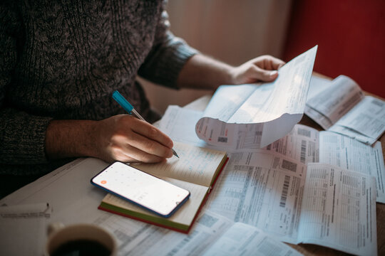 Close-up of men's hands with a calculator and utility bills. The concept of rising prices for heating, gas, and electricity. Lots of utility bills and hands with a calculator and a notebook