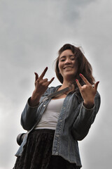 A female mexican photographer with brown hair making the rock n roll sign.