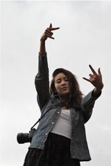A female mexican photographer with brown hair making the rock n roll sign.