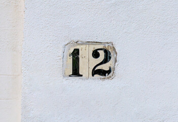 Street address number, number 12. What tile with black numbers on a white stucco background.