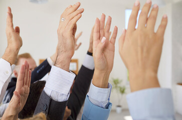 Closeup of business people hands raising hands to vote at the conference standing in meeting room....