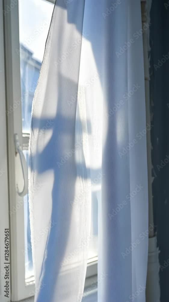 Poster light filtering through sheer curtain by a window creates soft shadows in a cozy indoor setting duri