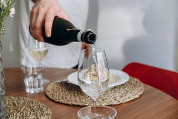 Pouring white wine or Prosecco into a glass from a bottle for an aperitif or dinner 