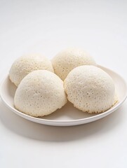 White rice cakes on a plain plate, ready for enjoyment. They could be sushi balls or simply delicious snacks.