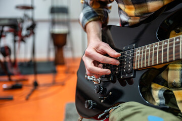 Man playing black electric guitar in recording studio
