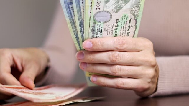 Close up view of woman hands counting cash money NPR (Nepalese rupees banknotes). Concept of saving money for retirement, cash settlement, financial success, literacy and income planning in Nepal.