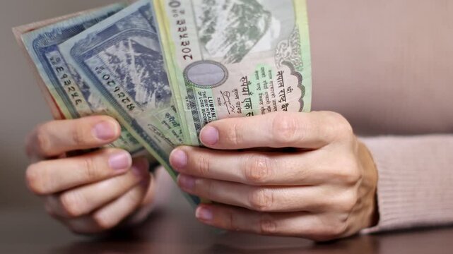 Close up view of woman hands counting cash money NPR (Nepalese rupees banknotes). Concept of saving money for retirement, cash settlement, financial success, literacy and income planning in Nepal.