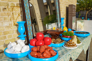 Festive table with symbols of Nowruz, including symbolic food items and additional items (book of poems, fish in a jar, mirror, etc.). Shot on the main street in Yazd, Iran