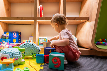 Child building towers with colorful blocks and exploring toys in a creative play space