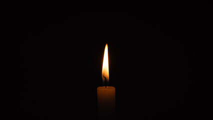 A burning candle on a black background
