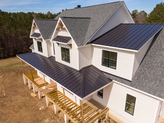 Sunny Daytime Drone Images of a Custom Home in the Final Stages of Construction. It Features a Roof With Architectural Asphalt Shingles and Standing Seam Accents. 