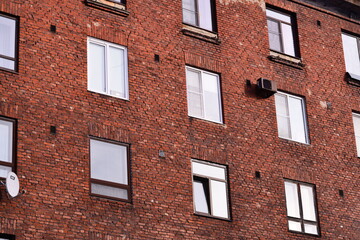 A brick building with multiple windows and a satellite dish, suitable for urban or modern scene...