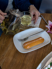 Person is pouring tea into a glass from a silver tea kettle