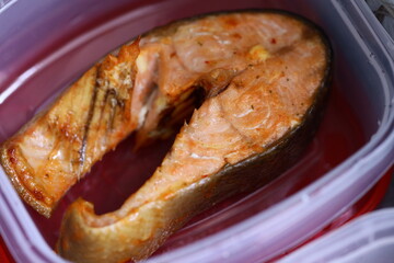 A piece of fresh salmon stored in a plastic container.