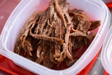 A plastic container filled with meat sits on a table.
