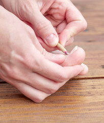 Person is using a pencil to file their nails