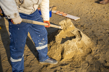 Man is shoveling sand into a pile