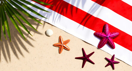 red and white striped beach towel with starfish and seashell on the sand