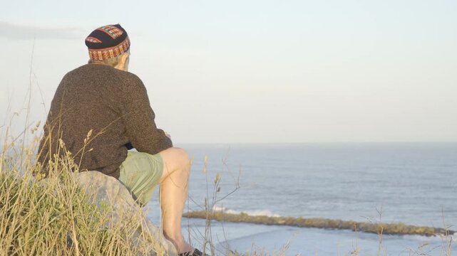 hombre anciano observando el mar desde altura
