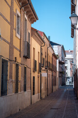Fototapeta premium Narrow street lined with colorful buildings in a historic neighborhood on a sunny day, Alcala De Henares, Spain