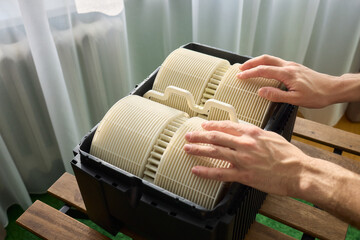 Hands are carefully handling industrial filters while inside a well-organized storage box