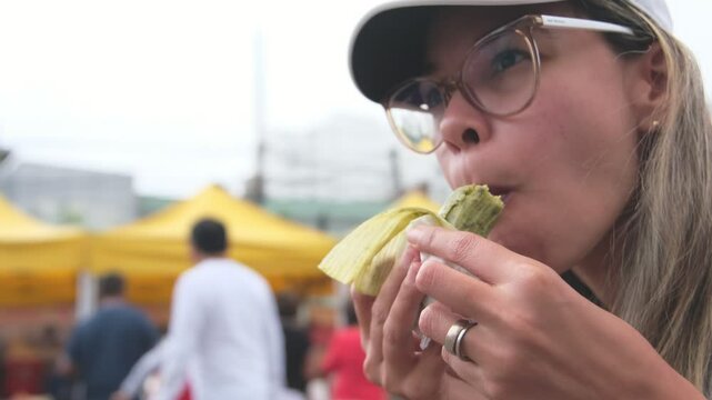 Young woman Enjoying green tamale in market farm, Peruvian street food.