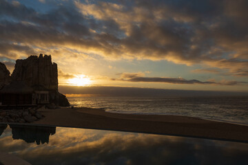 The sun and its rays breaking through at dawn over the Sea of Cortez and reflecting in the pool by the beach.