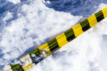 Bright yellow caution tape lies across a blanket of fresh snow, indicating a potential hazard or restricted zone during the winter season