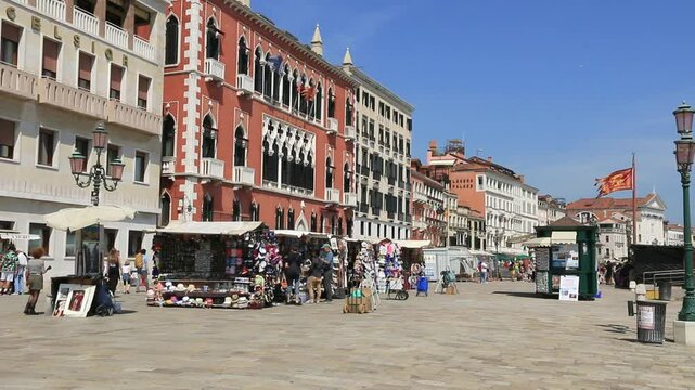 Le quai au bord du Grand canal parsem&eacute; d'&eacute;choppes et commer&ccedil;ants &agrave; Venise.