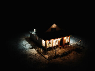 Lonely illuminated house among darkness, aerial view. Loneliness and solitude concept