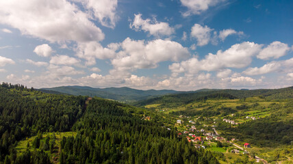 Majestic Mountains, Lush Green Forests, And Soft White Clouds On A Sunny Day. Aerial View Showcasing The Stunning Beauty Of Nature From A High Perspective.	
