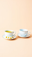 cup of herbal tea with chamomile flowers and an empty cup