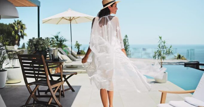 Back, woman and walking to swimming pool on holiday for peace, resort view or relax on chair. Vacation, smile or person by water at hotel for travel, luxury or fashion influencer with freedom outdoor