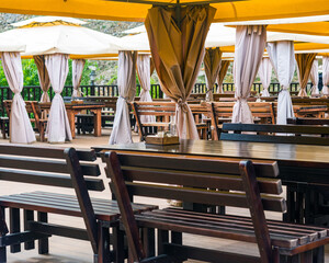 close-up of open-air restaurant with wooden floor tents over tables and benches. natural light